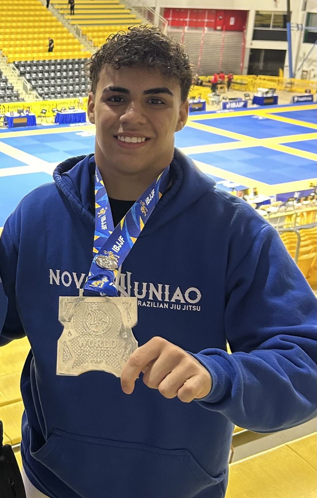 Antonio sorrindo e mostrando a medalha com o moletom da Nova União